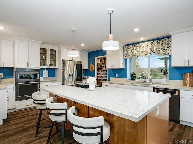 kitchen featuring sink, white cabinetry, a center island, pendant lighting, and black appliances