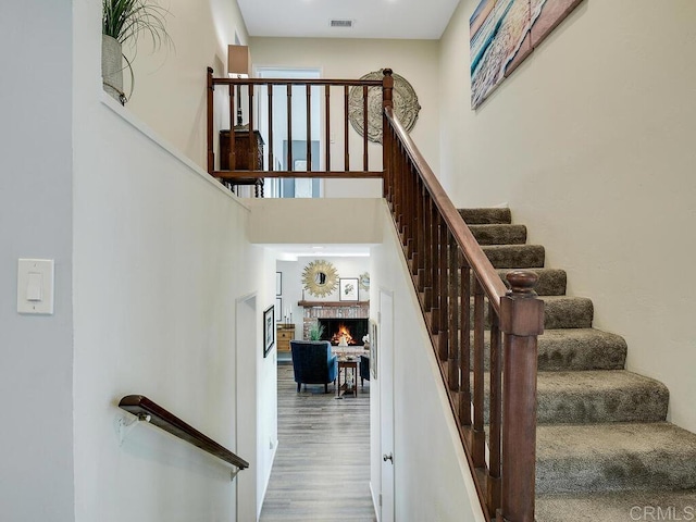 stairway with hardwood / wood-style flooring and a towering ceiling