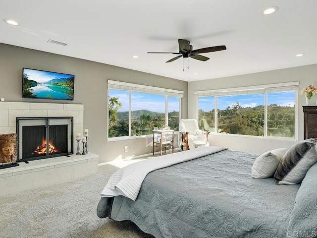 bedroom with ceiling fan, a fireplace, carpet floors, and multiple windows