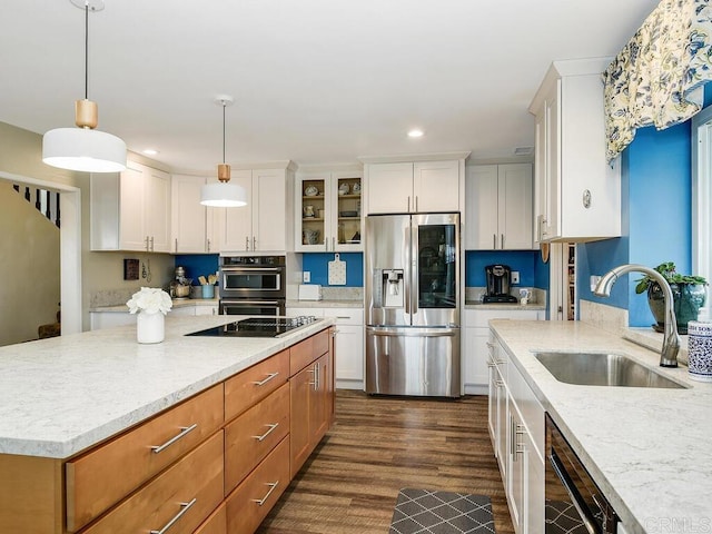 kitchen with sink, light stone counters, black appliances, white cabinets, and decorative light fixtures