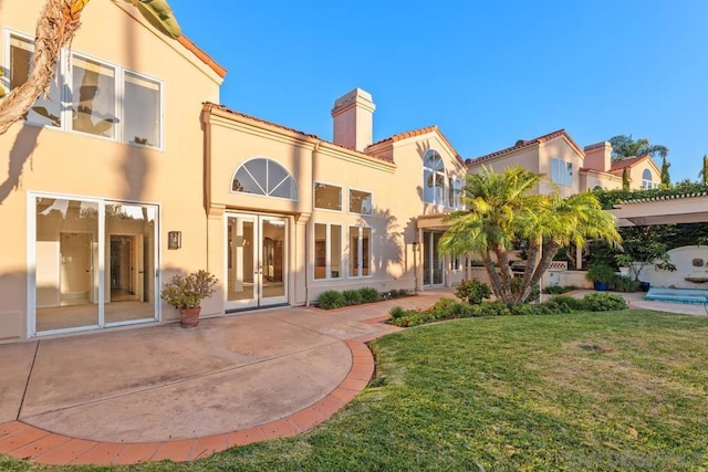 rear view of property featuring a patio area and a lawn