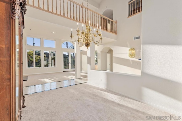 interior space featuring an inviting chandelier, a towering ceiling, and carpet floors