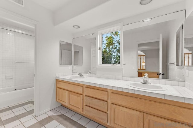 bathroom featuring tiled shower / bath, tile patterned floors, and vanity