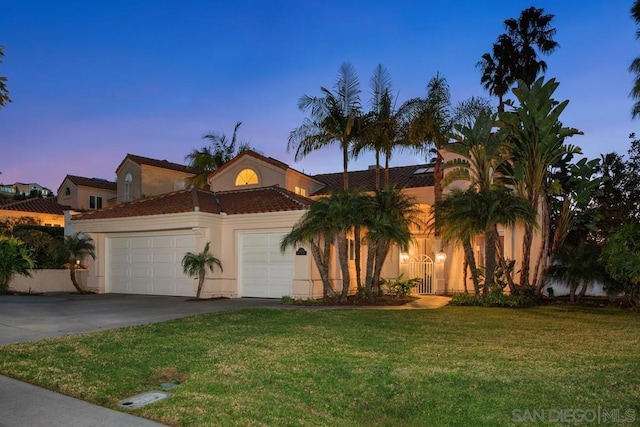 mediterranean / spanish-style house featuring a garage and a lawn