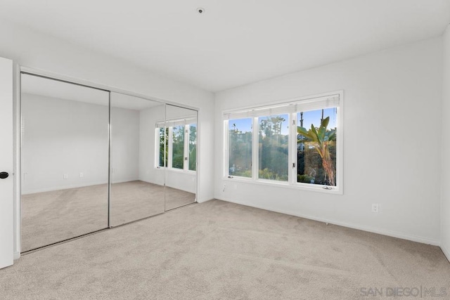 unfurnished bedroom with light colored carpet and a closet