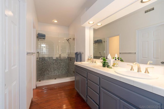 bathroom with wood-type flooring, vanity, and a shower with shower door