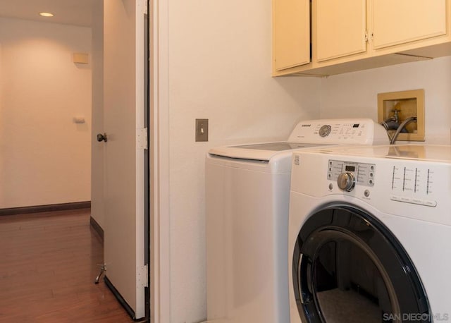 clothes washing area with dark hardwood / wood-style floors, washing machine and dryer, and cabinets