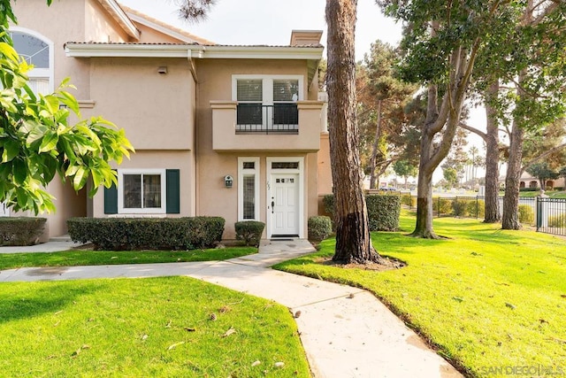 view of front of home featuring a balcony and a front yard