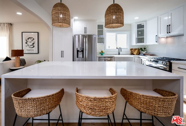 kitchen with appliances with stainless steel finishes, a center island, pendant lighting, and white cabinets