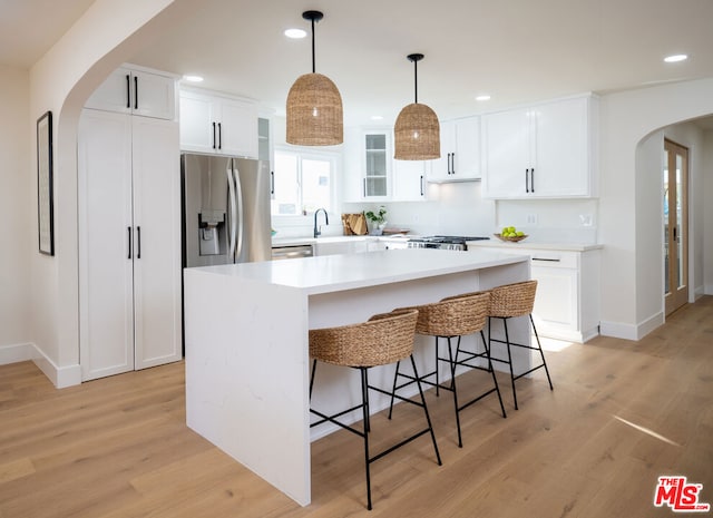 kitchen with pendant lighting, appliances with stainless steel finishes, a kitchen island, and white cabinets