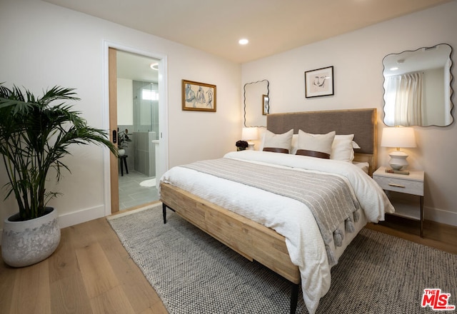 bedroom featuring hardwood / wood-style flooring and connected bathroom