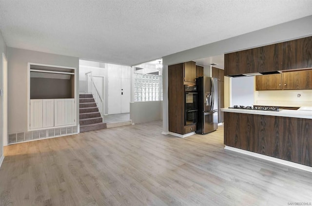 kitchen featuring light hardwood / wood-style flooring, black appliances, and a textured ceiling