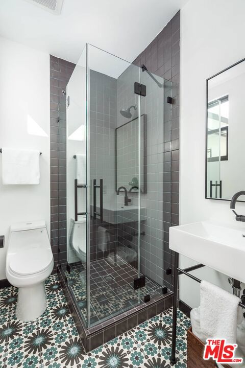 bathroom featuring walk in shower and toilet