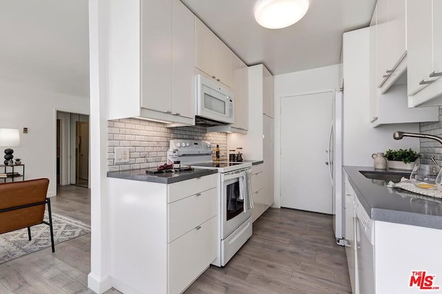 kitchen featuring sink, white appliances, white cabinetry, backsplash, and light wood-type flooring