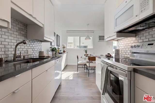 kitchen with tasteful backsplash, sink, white appliances, and white cabinets