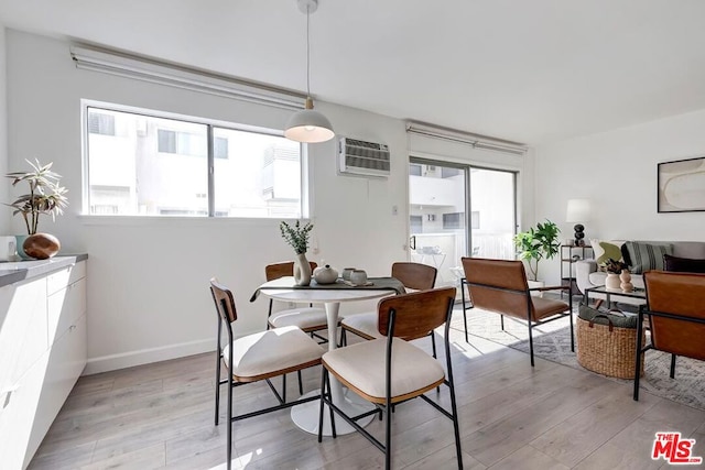 dining area with a wall mounted air conditioner and light hardwood / wood-style floors