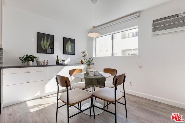 dining room featuring a wall mounted AC and light hardwood / wood-style flooring