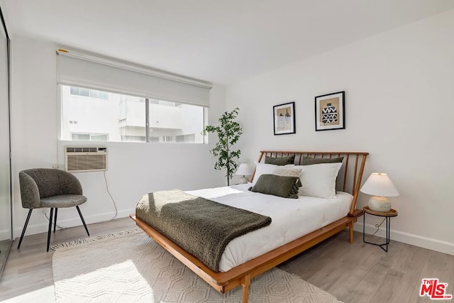 bedroom with cooling unit and light hardwood / wood-style flooring