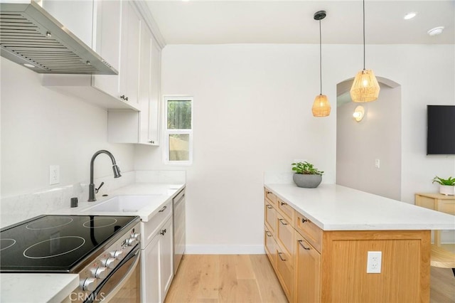 kitchen featuring appliances with stainless steel finishes, white cabinetry, sink, kitchen peninsula, and wall chimney range hood