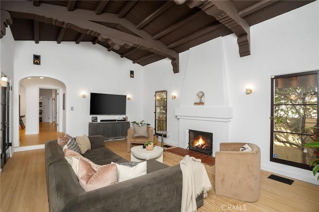 living room with beam ceiling, a fireplace, wooden ceiling, and light wood-type flooring