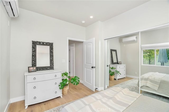 bedroom featuring a wall mounted air conditioner, a closet, and light wood-type flooring