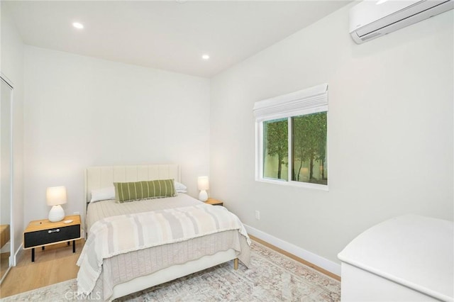 bedroom featuring hardwood / wood-style flooring and an AC wall unit