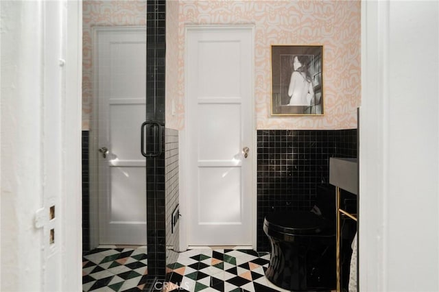 bathroom featuring tile walls and toilet