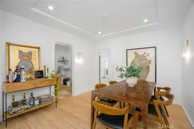 dining space with a tray ceiling and light hardwood / wood-style floors