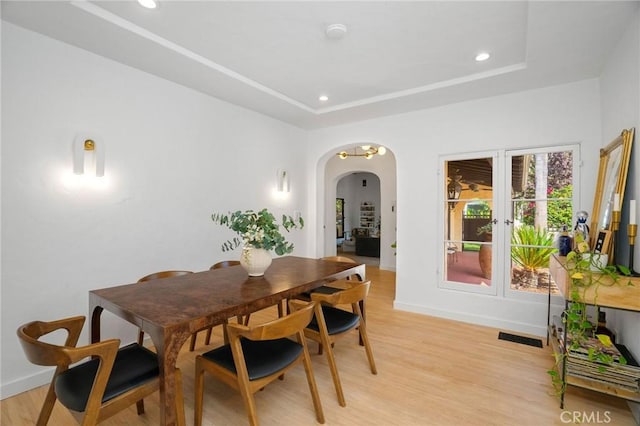 dining room with a raised ceiling and light wood-type flooring