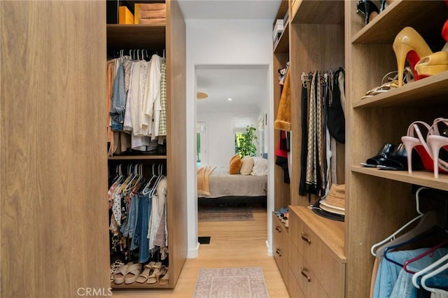 walk in closet with light hardwood / wood-style floors