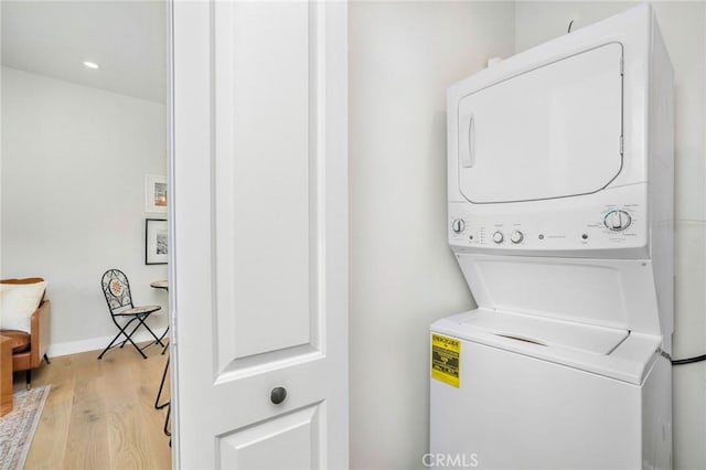 washroom with light hardwood / wood-style floors and stacked washer and clothes dryer