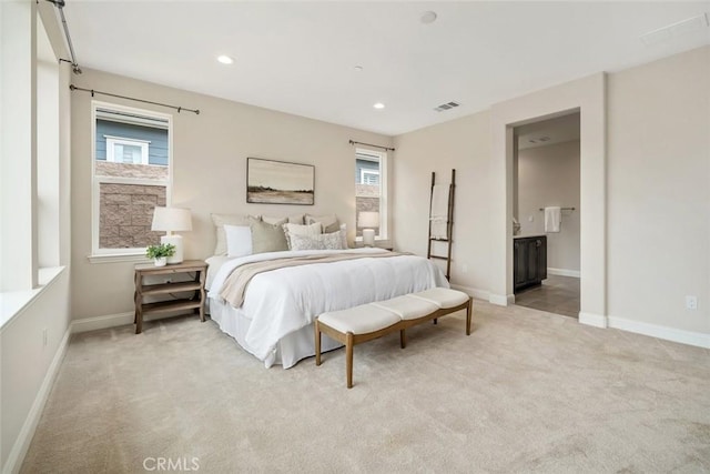 carpeted bedroom featuring multiple windows and ensuite bathroom