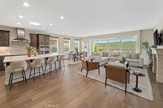 living room with a healthy amount of sunlight, sink, and light hardwood / wood-style flooring