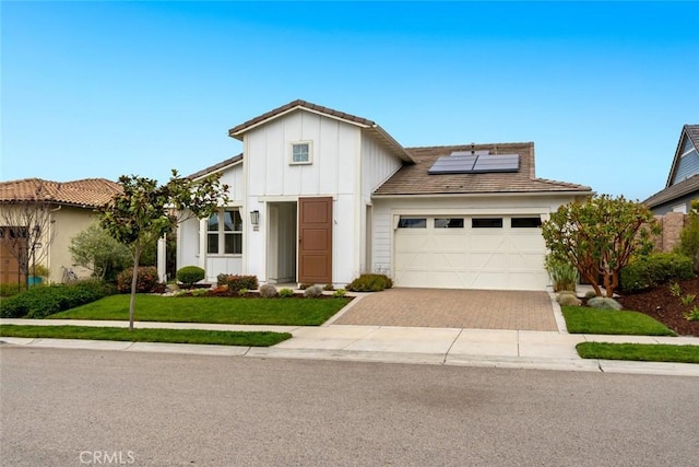 view of front of house featuring a garage, a front lawn, and solar panels