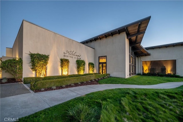 property exterior at dusk with a lawn