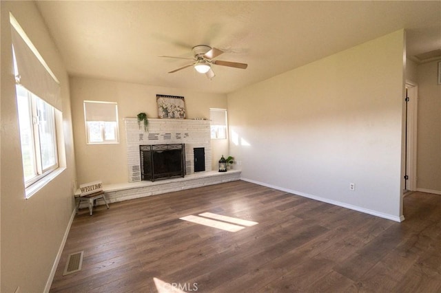 unfurnished living room featuring ceiling fan, dark hardwood / wood-style floors, and a brick fireplace