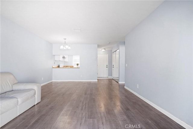 3738 Harrison St Unit 31, Riverside, CA 92503 - unfurnished living room featuring an inviting chandelier, dark wood-style floors, and baseboards