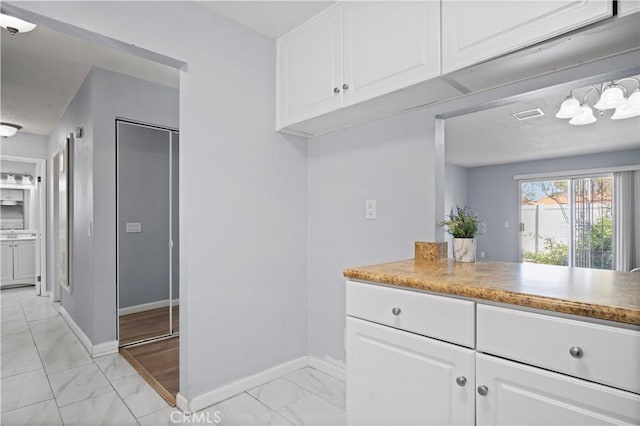 3738 Harrison St Unit 31, Riverside, CA 92503 - kitchen with light countertops, marble finish floor, baseboards, and white cabinetry