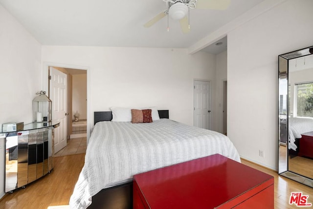 bedroom featuring vaulted ceiling with beams, light hardwood / wood-style flooring, and ceiling fan