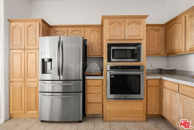 kitchen featuring stainless steel appliances, tile counters, and light brown cabinets