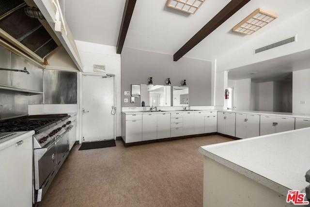 kitchen with sink, beamed ceiling, white cabinets, and range with two ovens