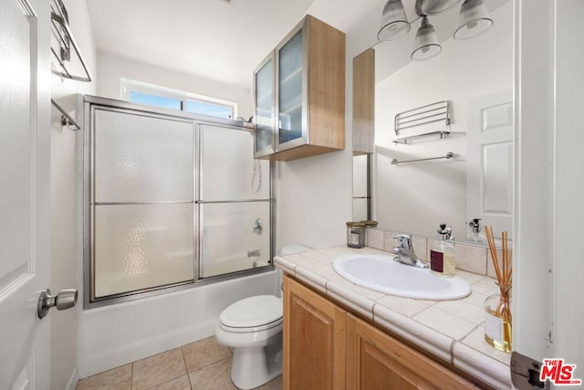 full bathroom featuring tile patterned flooring, vanity, shower / bath combination with glass door, and toilet