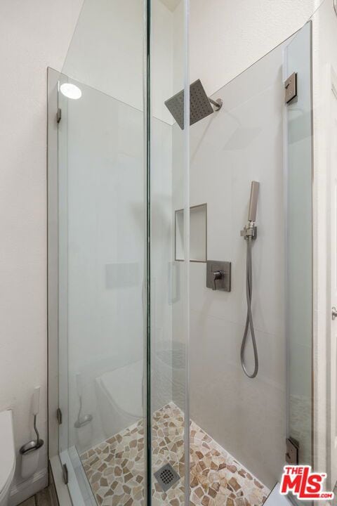 bathroom featuring a shower with door and toilet