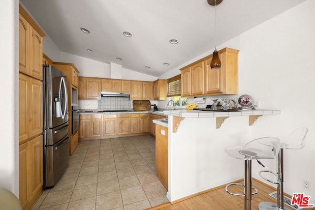 kitchen featuring pendant lighting, a breakfast bar area, stainless steel fridge with ice dispenser, tile countertops, and kitchen peninsula