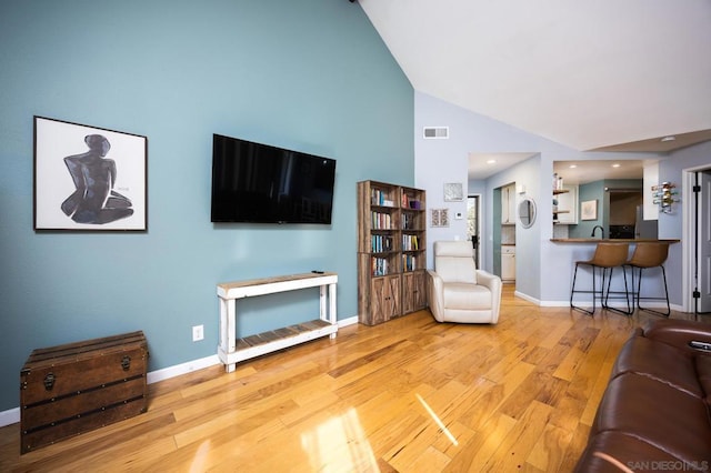 living room with high vaulted ceiling and light hardwood / wood-style flooring