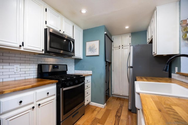 kitchen with wood counters, white cabinetry, light hardwood / wood-style floors, and appliances with stainless steel finishes