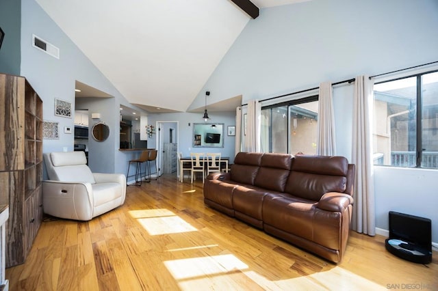 living room with beam ceiling, high vaulted ceiling, and light wood-type flooring