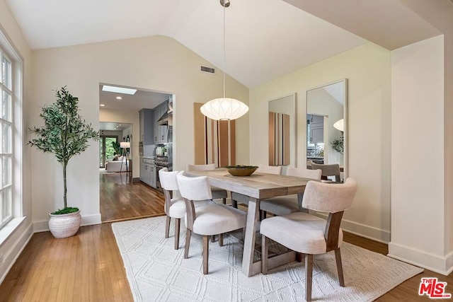 dining area featuring hardwood / wood-style flooring, vaulted ceiling, and plenty of natural light