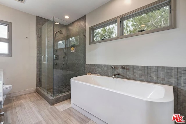 bathroom with plus walk in shower, tile walls, and toilet