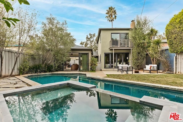 rear view of property with a fenced in pool, a patio area, outdoor lounge area, and a balcony